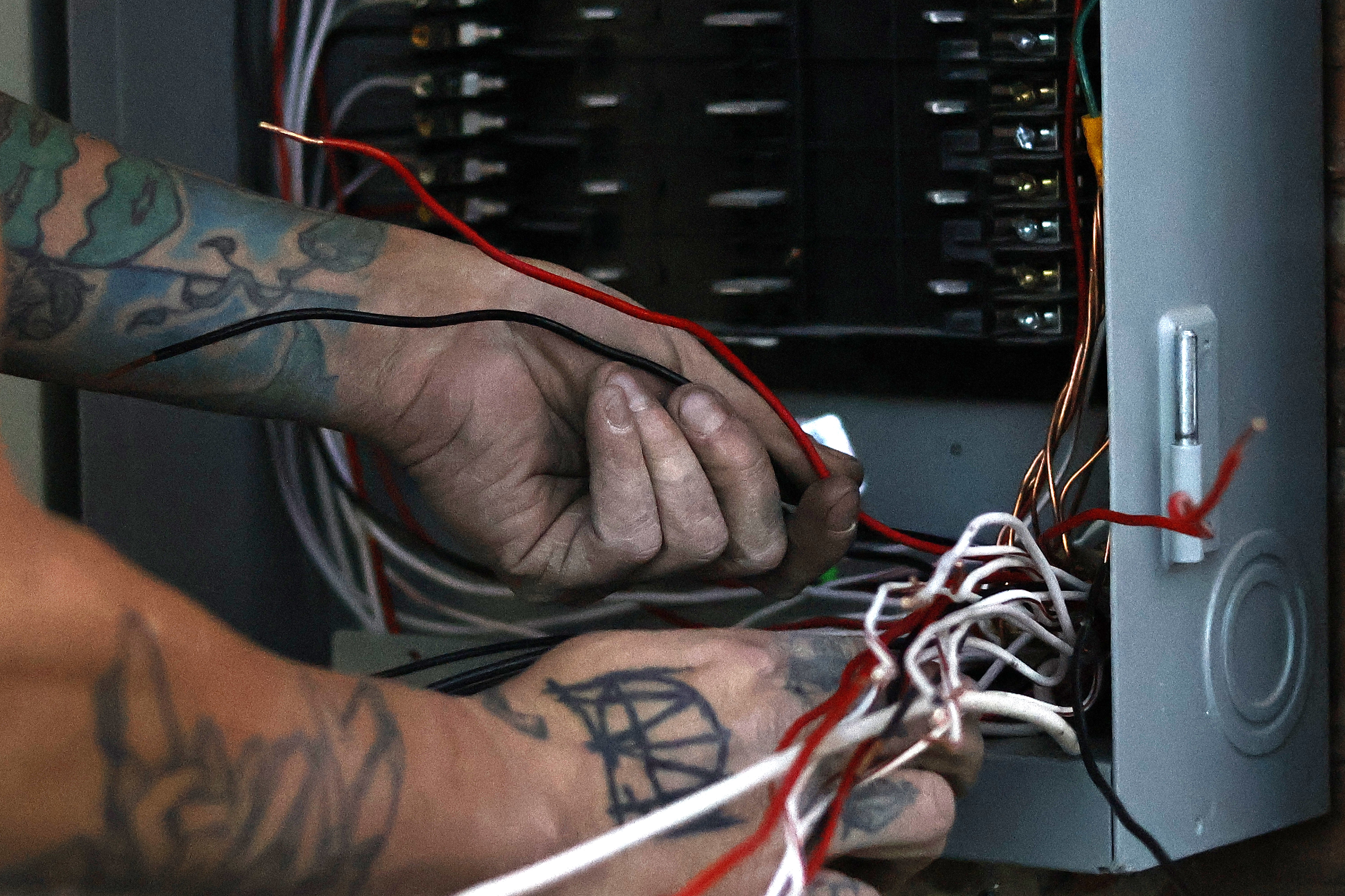 Electrician hands working with commercial wiring — Rise Above Electric Denver