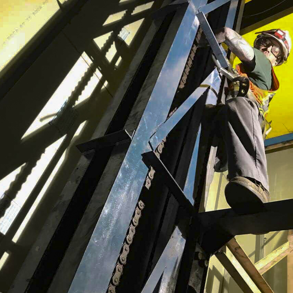 Electrician in safety helmet working on high scaffolding at commercial facility in Denver
