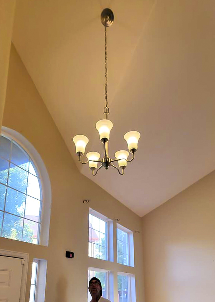 High-ceiling living room with chandelier installed by Rise Above Electric, Denver