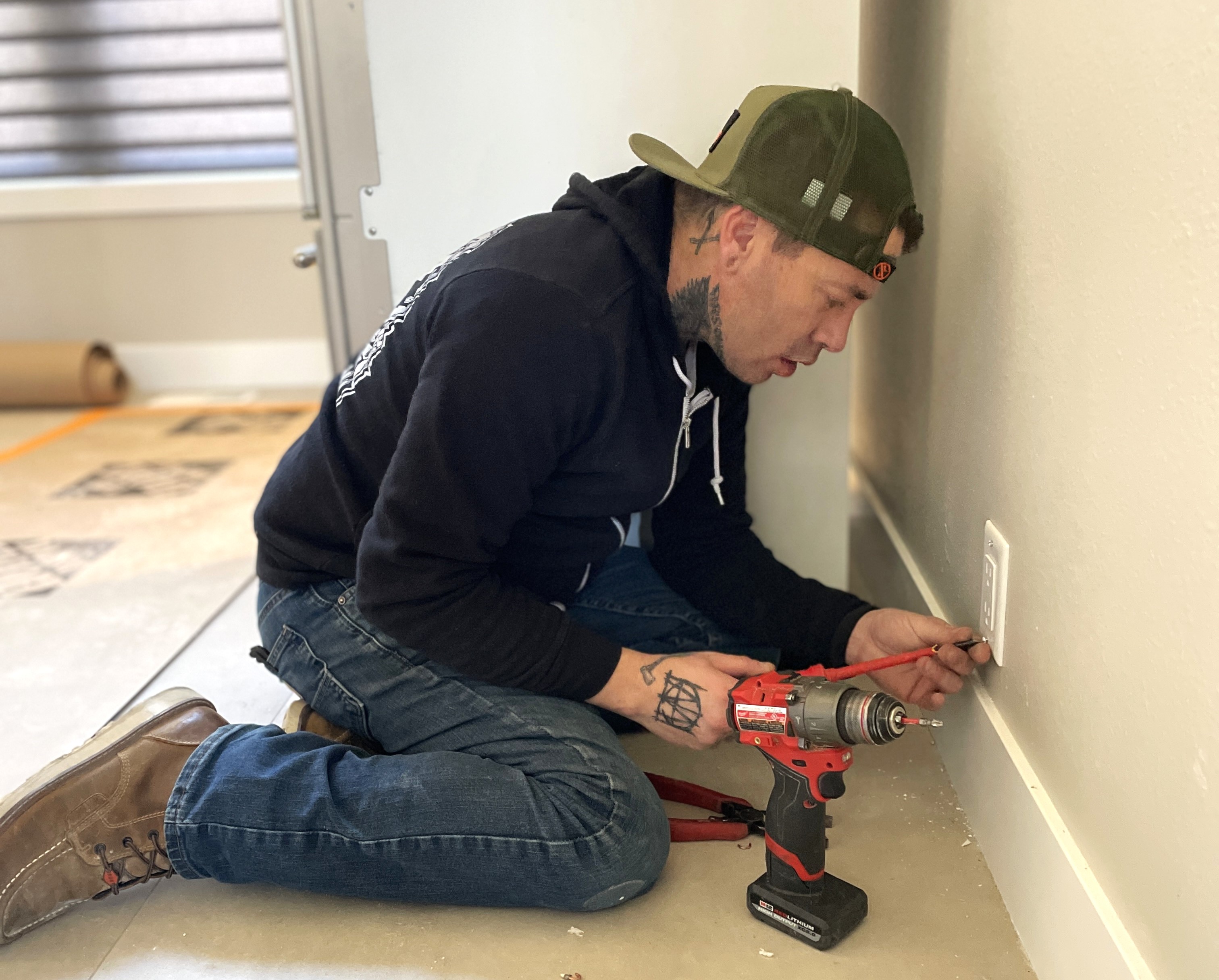 Electrician kneeling and troubleshooting electrical issue — Rise Above Electric Denver